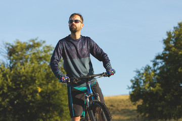 Naklejka premium A cyclist rides the hills, Beautiful portrait of a guy on a blue bicycle