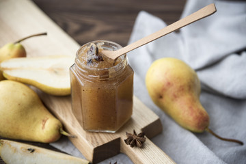  jar of pear jam and fresh pears on a dark wooden background