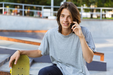 Young skater guy sit in the park with skateboard. © Drobot Dean