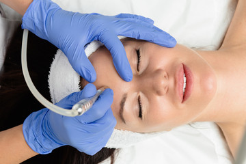 Beautiful woman getting facial microdermabrasion peeling treatment at luxury cosmetic beauty spa...