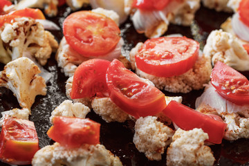 Baked cauliflower with tomato, onions and spices, vegan, close-up