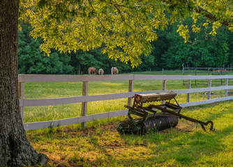 La Plata, Maryland, USA - May 11, 2018: Sunset on the farm with a plow in front of a fence