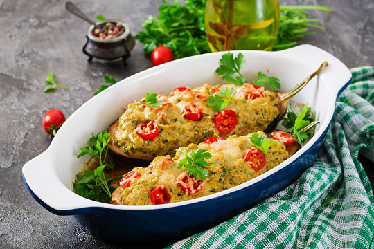 Minced meat chicken and vegetables stuffed eggplants on a grey background. Dinner food.