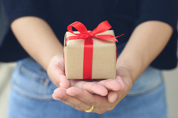 Selective focus of Woman hand holding gift box with white ribbon for Christmas and New Year's Day or Greeting season