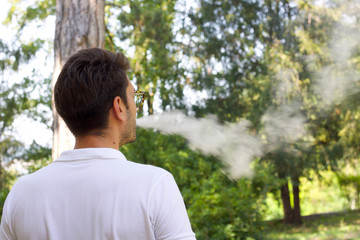 young man emitting steam from the electronic cigarette