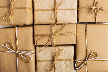 Gifts from Kraft paper lie tightly to each other on a white table. Christmas background.