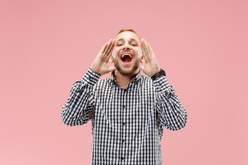 Do not miss. Young casual man shouting. Shout. Crying emotional man screaming on pink studio background. male half-length portrait. Human emotions, facial expression concept. Trendy colors