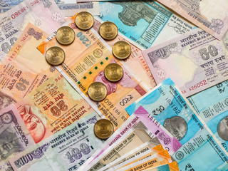 Question mark with indian coins. 10, 20, 50, 100, 200, 500 and 2000 Indian rupees, old and new notes in background.