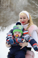 Young mother walks on a winter day with a baby in her arms in th