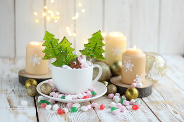 Fototapeta na wymiar Christmas still life with sweets, marshmallows, candies in cup and candles on wooden table. Christmas and new year holidays background. winter festive season. Advent time.