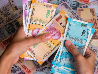 Woman's hands holding indian notes. 10, 20, 50, 100, 200, 500 and 2000 Indian rupees, old and new notes.