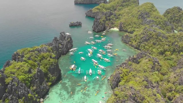 Aerial drone shot around paraw boats, in a turquoise lagoon, surrounded by limestone cliff islands, on a sunny day, on Palawan island, in Philippine archipelago, Philippines, Asia