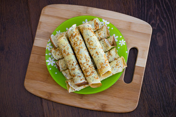 Pancakes rolls with cottage cheese on a wooden board. Pancakes with cheese. Shrovetide.