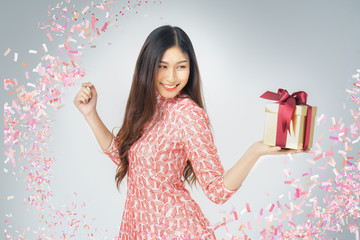 Photo of asian curious woman in red dress rejoicing her birthday or new year gift box. Young woman holding gift  box with red bow being excited and surprised  holiday present isolated white background