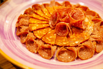 Assortment of tasty and delicious Italian antipasto delicatessen. Chorizo sausage and Salami and cold cuts on a colorful plate. A perfect appetizer, party snack or good accompany with wine.
