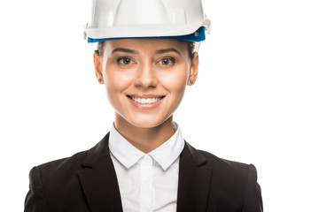 close-up shot of smiling young female architect in helmet and suit isolated on white