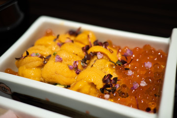 Tasty and delicious Sushi Donburi or Japanese rice bowl topped with fresh and creamy Sashimi Uni or Sea Urchin and Ikura or seasoned salmon roe at a restaurant. Healthy Eating and Eat Well Concept.