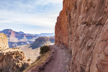 Rock face hiking trail down the Grand Canyon with a view of the famous rock formations on the background.