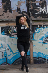 A girl in dark clothes dances 'Vogue' dance on a sports ground for skateboarders with painted graffiti walls