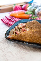 Black wheat and wheat galette topped with cooked ham and emmental cheese