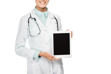 partial view of happy female doctor in medical coat showing digital tablet with blank screen isolated on white