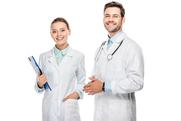 happy female doctor holding clipboard while her male colleague standing near isolated on white