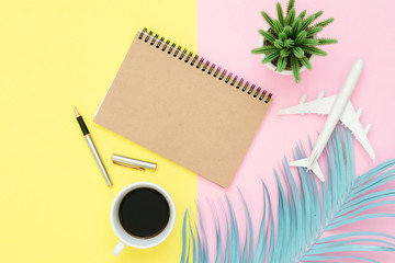 Flat lay design of travel summer concept - Top view mockup of blank paper notebook, pen, pastel leaf, coffee and plane on pink yellow pastel color screen. Travel in summer on pastel color background.