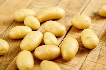 lots of fresh and young potatoes on an old wooden table in the kitchen