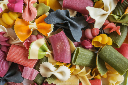 Mixed set of dry multi-colored Italian pasta on a white old wooden box. Background. Close up.