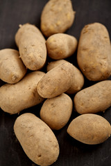 lots of young and fresh potatoes on a black wooden table in the kitchen