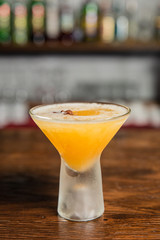 A photo of an orange alcoholic drink in a cocktail glass on a bar counter.
