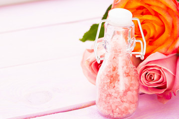 Spa and wellness setting with rose flower, sea salt, oil in a bottle on wooden white background