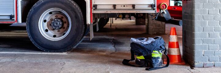 Panormic photo of a fire station with a fire truck and trousers prepared for clothes