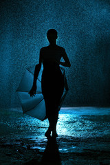 silhouette of the figure of a young girl with an umbrella in the rain, a young woman happy to drops of water