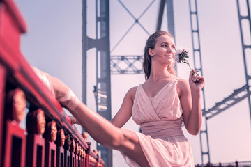 Wonderful aroma. Nice young woman smelling a beautiful flower while dancing on the bridge © Viacheslav Yakobchuk