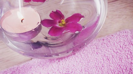 Obraz na płótnie Canvas Romantic composition with a candle and violet flowers floating in a bowl of water.The concept of Spa,cosmetic,procedure,treatment.