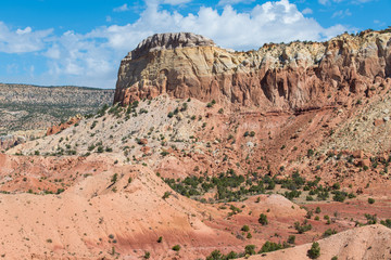 Colorful valley, cliffs, and mesa under a bright blue sky with puffy white clouds near Abiquiu, New Mexico in the American Southwest