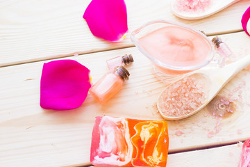 Spa and wellness setting with rose flower, sea salt, oil in a bottle on wooden old background