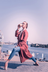 Favourite drink. Nice attractive woman holding a cup of coffee while standing in the dancing position © Viacheslav Yakobchuk