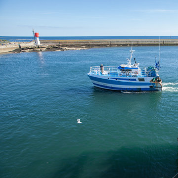Fototapeta Un chalutier bleu et blanc entre dans le port breton du Guilvinec (Finistère)