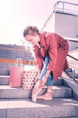 After shopping. Nice beautiful ballerina fixing her shoes while standing near her shopping bags © Viacheslav Yakobchuk