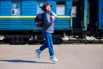 60 year old woman with backpack at railway station. Travel concept