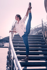 Very beautiful. Nice elegant woman holding her leg up while dancing on the stairs © Viacheslav Yakobchuk