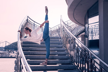 Graceful movements. Pleasant skilled dancer holding her leg up while standing on the stairs © Viacheslav Yakobchuk