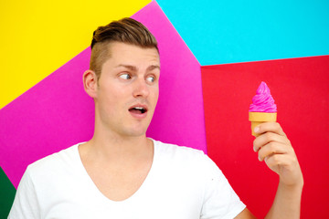 blond man in front of colorful background holding an icecream