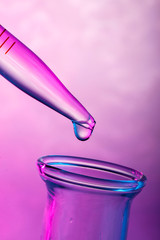 Close up on a drop on tip of pipette in pink light