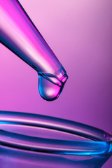 Close up on a drop on tip of pipette in pink light