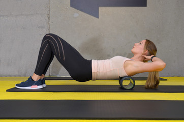 Young blonde woman training with roller at gym