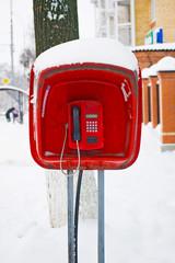 Old street public payphone on the street close-up. Red pay phone in the booth.