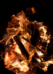 Charred wood and bright flames on dark background